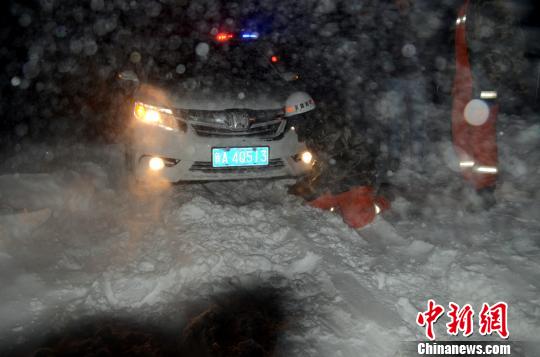 圖為消防人員跪在雪地里用鐵鍬鏟雪救援被困車輛?！±罱z